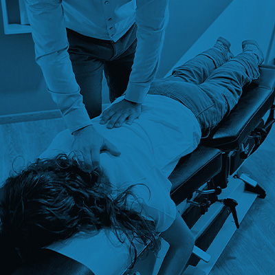 Chiropractic patient on table getting back checked by chiropractor.