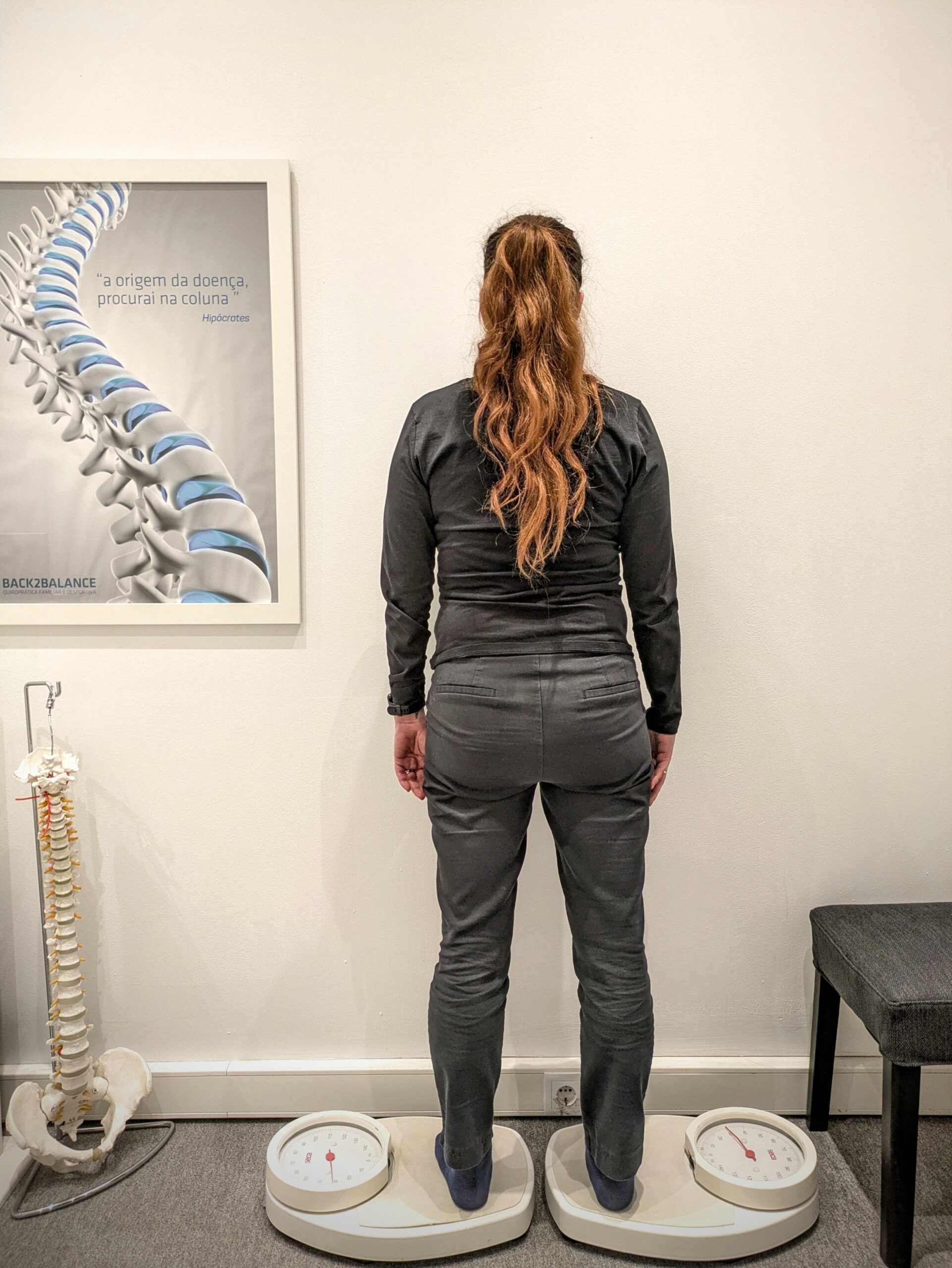 A woman standing on two separate scales during a chiropractic postural assessment at Back2Balance, evaluating weight distribution and spinal alignment.